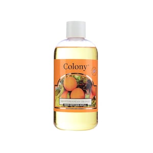 Puede incluir: Una botella de vidrio transparente con un líquido amarillo en su interior. La botella tiene una tapa blanca y una etiqueta que dice "Colony" y "Recarga de difusor de caña de naranja mediterránea". La etiqueta también presenta una imagen de naranjas en una rama.