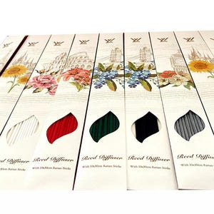 May include: Ten reed diffusers with various coloured reeds, each with a label that reads "Reed Diffuser with Ultrasonic Bamboo Sticks". The labels have a floral design and the words "Reed Diffuser" are in a script font.