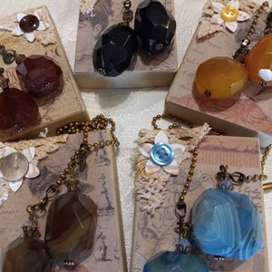 May include: Set of five pairs of decorative tassel pulls with various colored agate stones. Each pair is attached to a gold chain and has a decorative metal top.