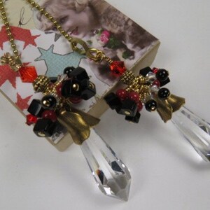 May include: A pair of crystal fan pulls with gold chains and black and red bead accents. The beads are arranged in a cluster and include small gold beads, black beads, and red beads.
