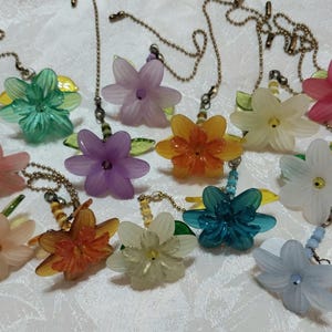 May include: A collection of colorful flower-shaped light pull chains. The flowers are in various colors, including pink, green, purple, orange, and white. Each flower is attached to a chain with a decorative bead.