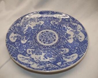 Plato antiguo de porcelana asiática con diseño floral de pájaro azul, firmado en la parte posterior.