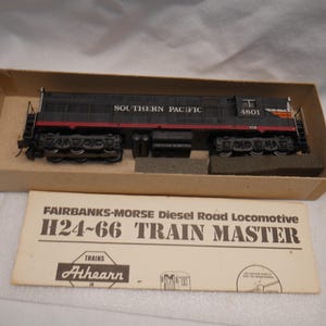 May include: A model Fairbanks-Morse H24-66 Train Master diesel road locomotive by Athearn, painted black with red stripes and the text SOUTHERN PACIFIC 4801. The model is housed in a cardboard box with an accompanying instruction sheet.