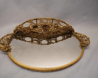 Espejo de tocador ovalado vintage de bronce dorado estilo Matson con soporte para brocha de lápiz labial