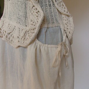 May include: A white crocheted top with a gathered skirt and a drawstring closure. The top has a delicate lace pattern and the skirt is made of a soft, lightweight fabric.