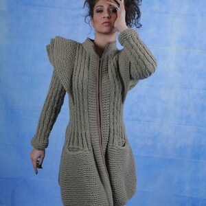 May include: A grey knitted cardigan with a zip fastening and large pockets. The cardigan has a textured knit pattern and a slightly flared silhouette.