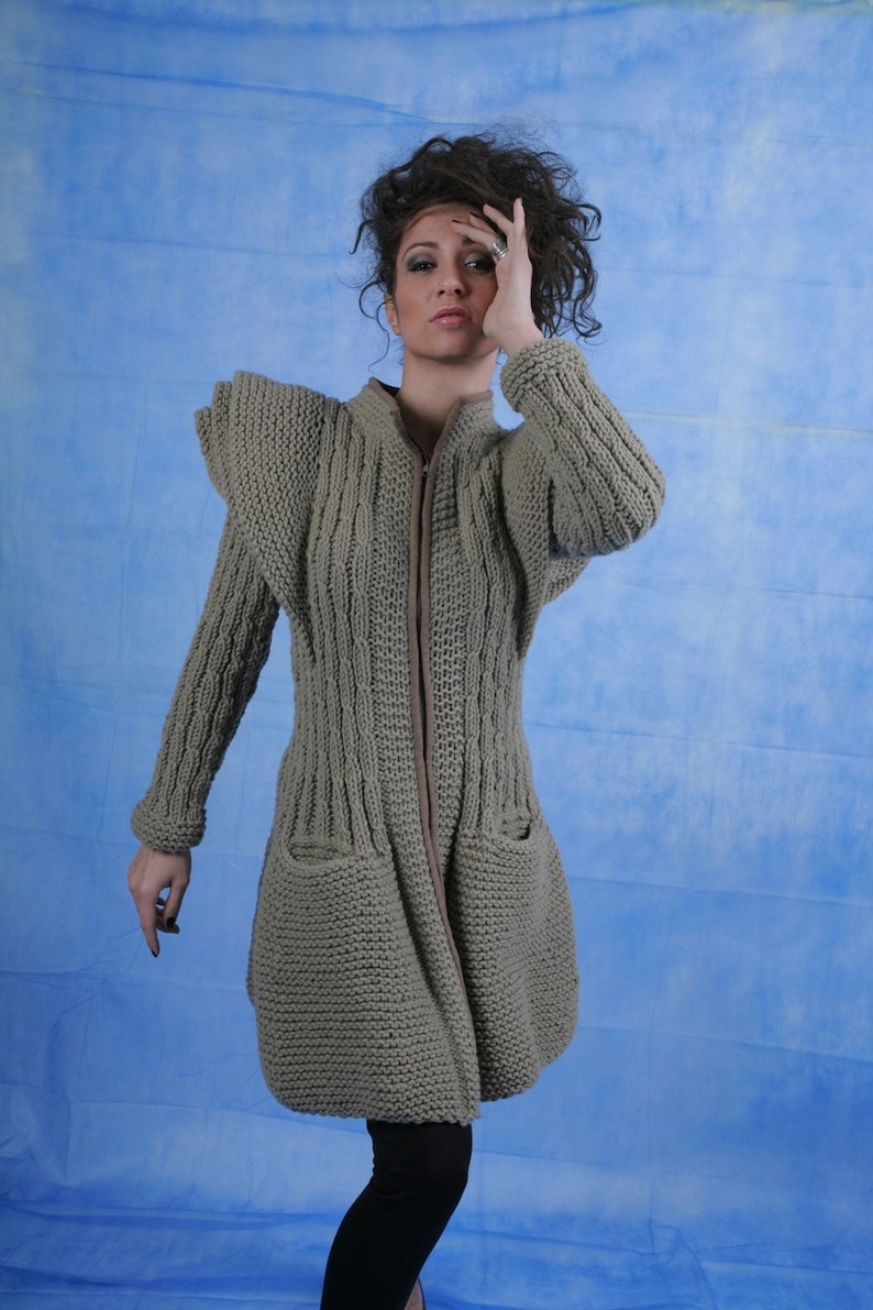 May include: A grey knitted cardigan with a zip fastening and large pockets. The cardigan has a textured knit pattern and a slightly flared silhouette.