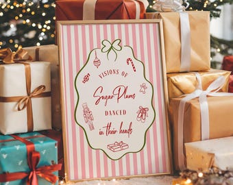 Könnte beinhalten: Ein gerahmter Druck mit dem Text "Visions of Sugar Plums danced in their heads" in roter Schrift, umgeben von weihnachtlichen Illustrationen. Der Druck befindet sich vor einer Kulisse aus verpackten Geschenken in Gold, Rot und Türkis, mit einem Weihnachtsbaum im Hintergrund.