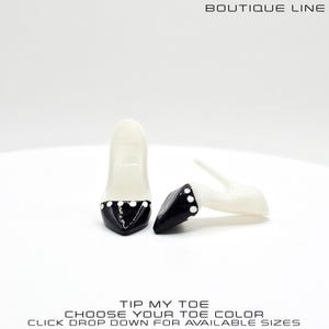 May include: Two high-heeled shoes, one upright and one on its side. The shoes are white with black toe caps adorned with white polka dots. The text "BOUTIQUE LINE" is at the top. The text "TIP MY TOE CHOOSE YOUR TOE COLOR CLICK DROP DOWN FOR AVAILABLE SIZES" is at the bottom.