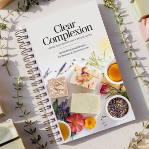 Puede incluir: Un libro blanco en espiral con el título "Clear Complexion" en texto negro. El libro está abierto en una página con el texto "50 Soothing Soap Recipes for Redness & Hormonal Acne". La página también presenta imágenes de barras de jabón y flores.