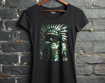 May include: A black short-sleeved t-shirt featuring a graphic print of a person wearing a feathered headdress with a digital glitch effect in shades of teal and white. The text WRATH IN THE MACHINE is printed in white at the top right corner.