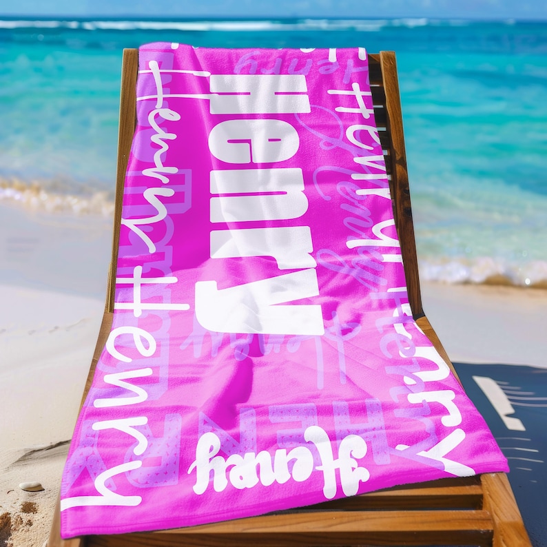 Bright pink personalized beach towel with the name Henry in multiple fonts, displayed on a lounge chair by the ocean. Custom name towel, ideal for pool, swim, or summer trips, and a unique gift for any age.