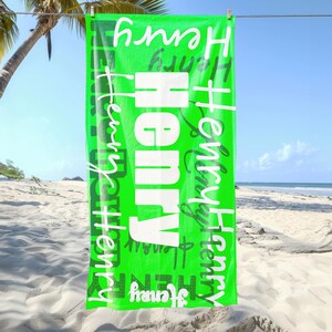 Bright green personalized beach towel with the name Henry in various fonts, hanging on a line at the beach with palm trees and sand. Custom name towel, perfect for pool, swim, or summer trips for all ages.