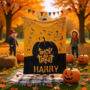 May include: A Halloween blanket featuring a black pumpkin design with the words "Trick or Treat" and "Harry". The blanket has a yellow backdrop with black spiderwebs, bats, and skeletons. Pumpkins and children are in the background.
