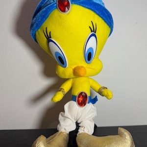 Op de afbeelding: Een pluche Tweety Bird verkleed als een geest, met een gele body, blauwe tulband met een rode edelsteen en gouden schoenen. Het figuur heeft een witte broek, gouden armbanden en een rode edelsteen op de borst.