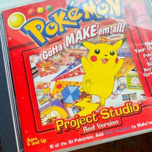 Op de afbeelding: Een Pokemon Project Studio Red Version CD-ROM. De cover toont een gele Pikachu-personage met uitgestrekte armen tegen een rode achtergrond. Tekst bevat "Gotta Make 'em all!" en "Make Your Own: Pokemon Cards, Stickers, Key Chains, Certificates, Signs, Tattoos, and More."