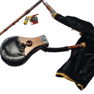 Puede incluir: Un juego de gaita desmontado. Los componentes incluyen una bolsa de terciopelo negro con ribetes dorados, tubos de madera y metal, un fuelle y pequeños accesorios. La gaita es un instrumento musical escocés tradicional.