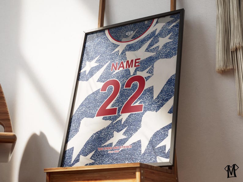 May include: Framed print of a jersey design with a blue and white star pattern. The jersey features the word "NAME" above the number "22" in red. The text "USA" is at the top.