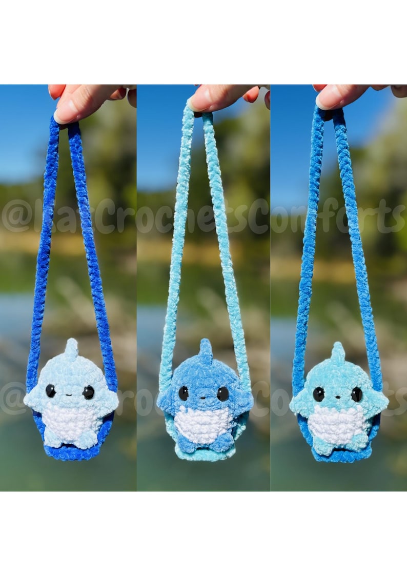 Pu&ograve; includere: Tre borse a forma di squalo in peluche in varie tonalit&agrave; di blu. Ogni borsa ha un cinturino blu abbinato. Le borse sono tenute contro uno sfondo sfocato verde e blu. Il testo "@ka CrochetsComforts" &egrave; visibile.