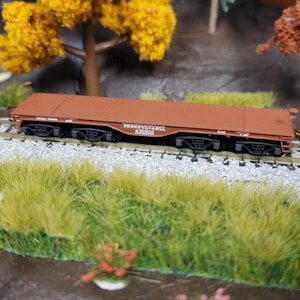 Könnte beinhalten: Ein brauner Modell-Wagen mit der Aufschrift "PENNSYLVANIA RAILROAD" an der Seite. Der Wagen steht auf einem Modell-Eisenbahn-Gleis.