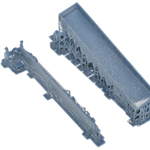 May include: Two gray model bridge structures. One is a long, narrow bridge, and the other is a wider, elevated bridge section. Both are detailed with structural supports and deck features, ideal for model railroad enthusiasts.