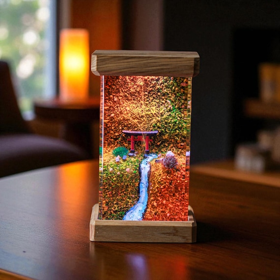 A handcrafted resin lamp where a glowing LED Torii gate floats inside a miniature fall forest — moody Japanese aesthetic in a desktop diorama.