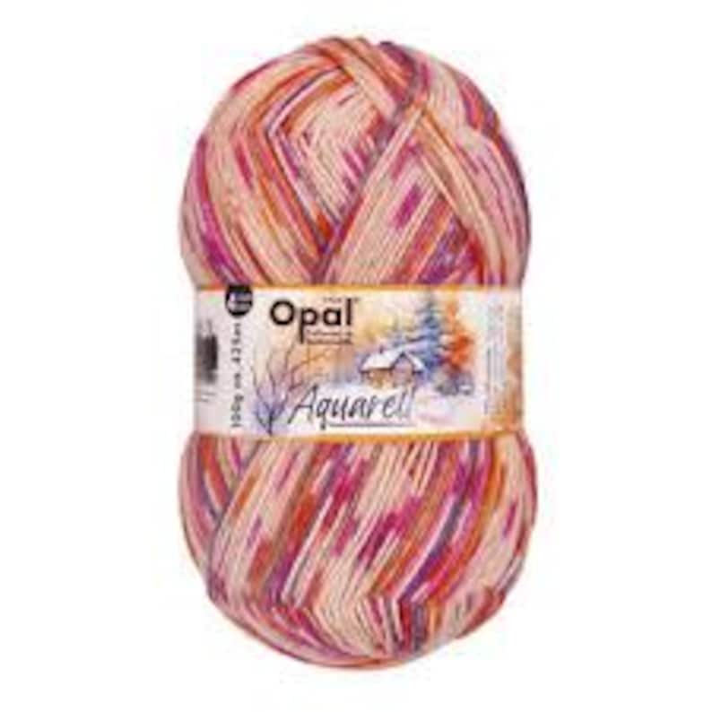 May include: A ball of Opal Aquarell yarn in shades of pink, orange, and cream. The yarn is 100g and 425m. The label features a winter landscape scene with the brand name "Opal".