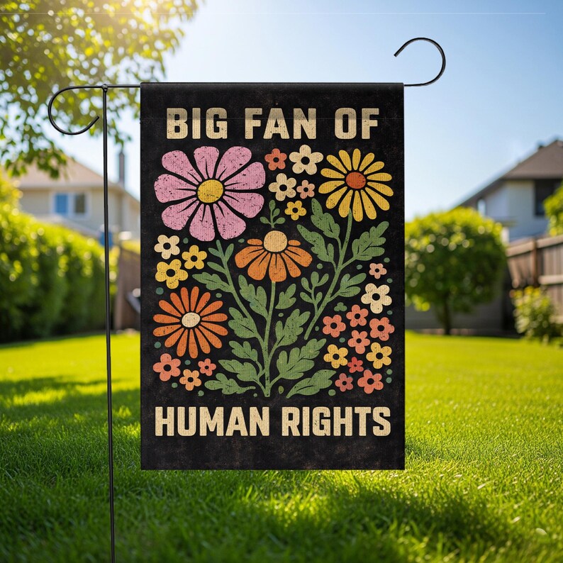 May include: A rectangular garden flag with a black background featuring the text BIG FAN OF HUMAN RIGHTS in a bold, light-colored font. The design includes a central illustration of various colorful flowers in pink, yellow, and orange.