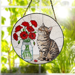 Op de afbeelding: Een ronde glas-in-lood zanger met een bruine cyperse kat die naast een doorzichtige glazen pot vol felrode klaprozen zit. De kat heeft de ogen gesloten en bevindt zich op een lichte ondergrond met een getextureerde achtergrond.