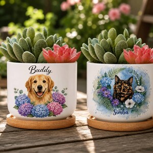 Könnte beinhalten: Zwei zylindrische Pflanzgefäße aus weißer Keramik mit Bambusuntersetzern, die jeweils eine grüne Sukkulente und eine rosa Blume enthalten. Eines zeigt einen Golden Retriever mit dem Namen Buddy, das andere eine Schildpattkatze mit dem Namen Simba.