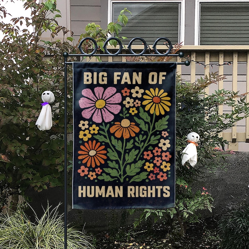 May include: A rectangular garden flag with a black background featuring a colorful floral illustration and the text "BIG FAN OF HUMAN RIGHTS" in a bold, light-colored font. The design includes pink, yellow, and orange flowers with green leaves.
