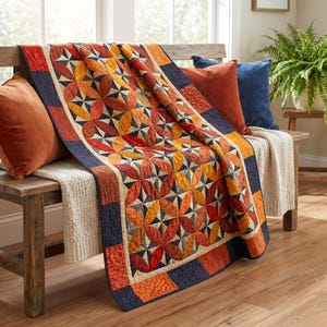Peut inclure: Une courtepointe présentant un motif répétitif de formes courbes orange, rouges et jaunes disposées en motifs circulaires avec des accents bleu foncé. La courtepointe a une bordure bleu foncé et est drapée sur un banc en bois avec des coussins.