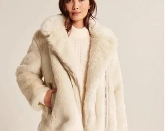 May include: A white faux fur jacket with a zipper closure. The jacket has a collar and a long sleeve design.