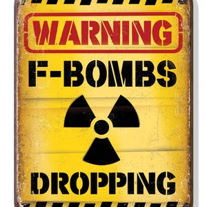 Può includere: Un cartello di avvertimento giallo con strisce nere, un simbolo di radiazione nero e il testo "WARNING F-BOMBS DROPPING".