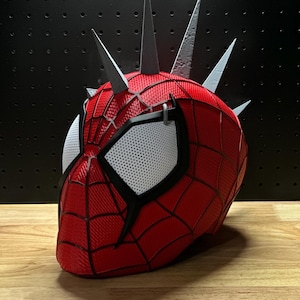 May include: A red and black Spider-Man mask with silver spikes. The mask features white mesh eye coverings and a webbed design. The mask is a cosplay item.