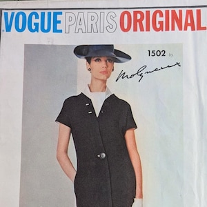 Puede incluir: Patrón de costura Vogue Paris Original número 1502 de Molynuex para un vestido negro con cuello blanco y mangas cortas. La modelo lleva un sombrero negro y guantes blancos.