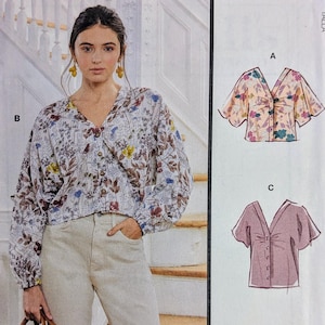 May include: McCall's sewing pattern featuring a woman wearing a floral print blouse. The pattern includes multiple view options with simple instructions. The image also shows illustrations of the blouse in different styles. Size Y (XS-S-M).