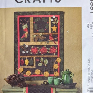 Puede incluir: Un patrón de colcha con temática navideña con un cardenal rojo, piñas y campanas. El patrón se llama "M4991" y es de Cheryl Haynes.