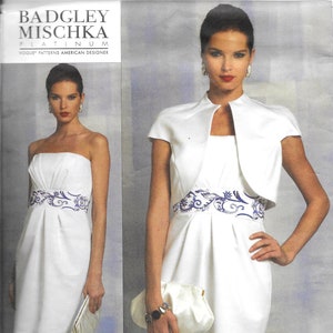 Könnte beinhalten: Ein weißes trägerloses Kleid mit einem blauen und weißen Blumendesign um die Taille. Das Kleid wird mit einer weißen Bolerojacke mit kurzen Ärmeln kombiniert. Die Muster-Nummer V1154 ist auf dem Bild gedruckt.