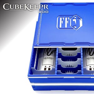 May include: A blue CubeKeeper 900 storage box with a white logo on the lid. The box is open, revealing interior compartments and two cylindrical containers. The text "SEND TO REMOVE SIDE DIVIDERS" is visible on the containers.