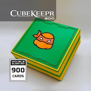 Può includere: Una scatola portaoggetti quadrata verde e gialla etichettata CubeKeepr 900. Il coperchio presenta una grafica con maschera da ninja arancione. Un'etichetta rettangolare bianca sulla scatola riporta la scritta Double Sleeved 900 Cards per carte.