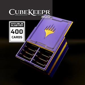 May include: A purple CubeKeepr 400 card storage box with a gold logo on the lid. The box features an open compartment with internal dividers and text that reads Double Sleeved 400 Cards. The design includes a hinged lid and gold accents.