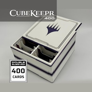 May include: A white and purple card storage box labeled CubeKeepr 400 with a purple planeswalker symbol on the lid. The box features internal dividers and is designed to hold 400 double sleeved cards as indicated by the text on the box.