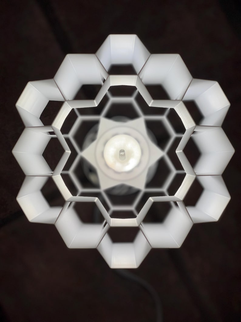 Op de afbeelding: Witte plafondlamp met een honingraatontwerp. De lamp is gemaakt van wit metaal en heeft een ronde vorm.