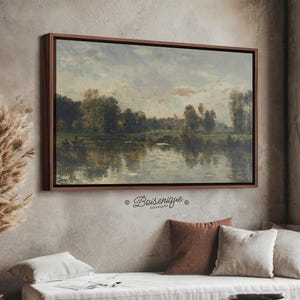 May include: A rectangular landscape painting in a dark wood frame depicting a calm river reflecting a line of trees under a cloudy sky. The artwork features muted green, brown, and blue tones with visible brushstrokes. The text Boisenique is printed below the frame.