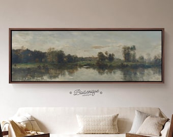 Könnte beinhalten: Gerahmtes Landschaftsgemälde, das eine ruhige Flussszene mit Bäumen und einem bewölkten Himmel zeigt. Das Kunstwerk weist gedämpfte Töne von Grün, Grau und Braun auf und erzeugt eine ruhige Atmosphäre. Das Gemälde wird über einem weißen Sofa ausgestellt.