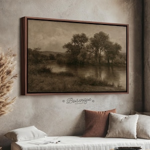 Op de afbeelding: Een rechthoekig landschapsschilderij in een donkerbruine lijst met een sepia-getinte scène van een rustige rivier die langs bomen en grasrijke oevers stroomt onder een bewolkte lucht. De tekst Boisenique Stunning Art staat in het zwart onder de lijst gedrukt.