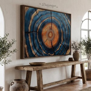 May include: Large framed artwork featuring a cross-section of a tree trunk, showcasing concentric rings in shades of blue and orange. The artwork is displayed above a rustic wooden console table, creating a natural and earthy aesthetic.