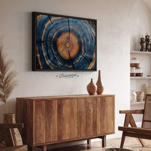 May include: A framed artwork featuring a cross-section of a tree trunk, showcasing concentric rings in shades of blue, orange, and brown. The artwork is mounted on a white wall above a wooden cabinet. Two decorative vases sit on top of the cabinet.