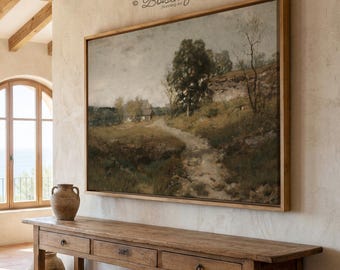 May include: A framed landscape painting depicting a path leading to a small house, with trees and a cloudy sky. The painting is in a wooden frame and hangs above a wooden console table. The room has a neutral color palette.